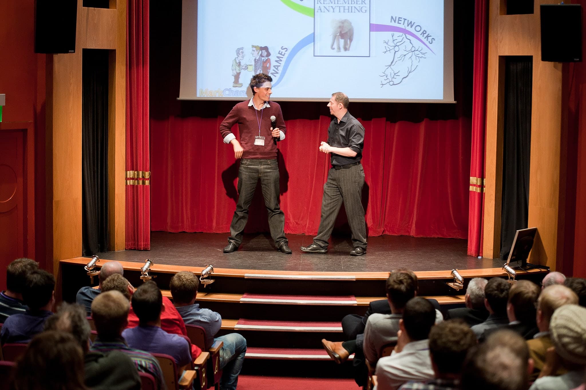 Mark on stage directing a volunteer through a scene in front of an audience